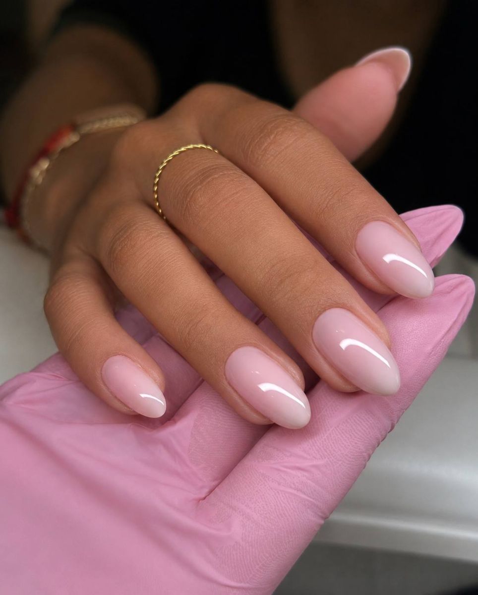 Milky-pink almond manicure with delicate gold rings, fresh from the chair
